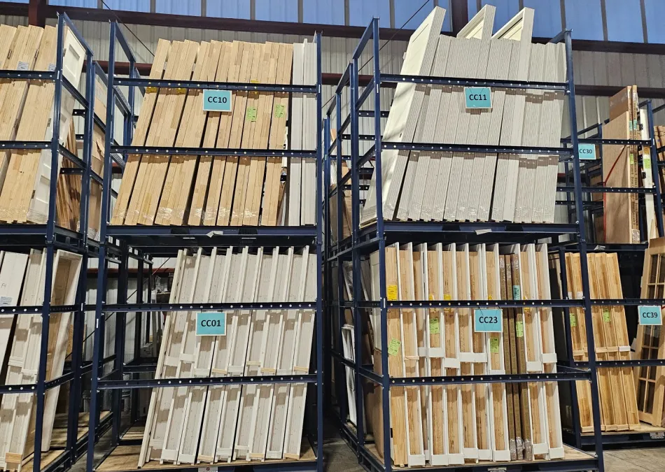Warehouse racks holding organized stacks of wood panels and boards inside an industrial storage facility.
