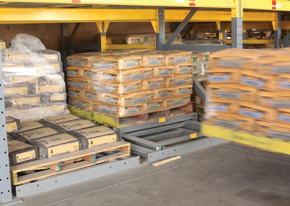Warehouse shelving with pallets of Quikrete cement bags stacked and moving on racks in industrial storage area