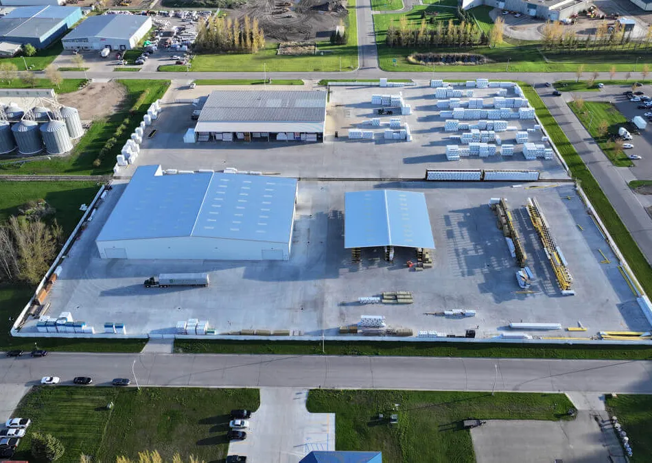 Aerial view of an industrial facility with large warehouses and organized storage areas in an urban setting.