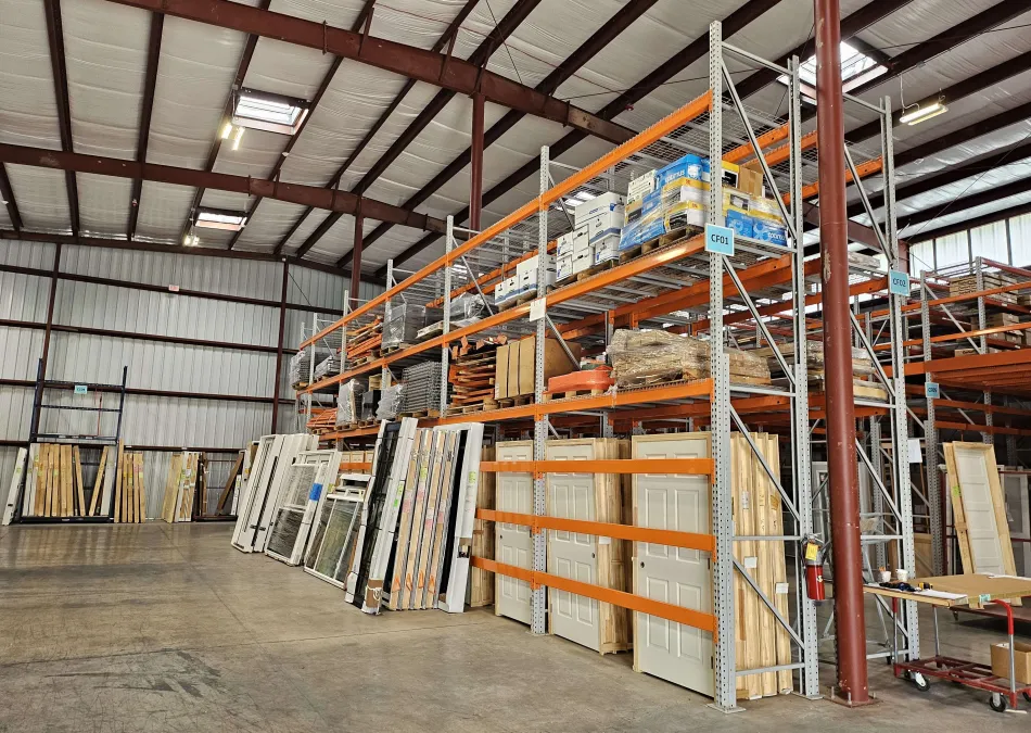 Interior of a warehouse with shelves holding doors, wooden panels, and construction materials organized neatly.