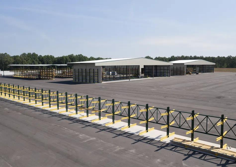 Large industrial yard with metal storage racks and warehouse buildings under a clear sky