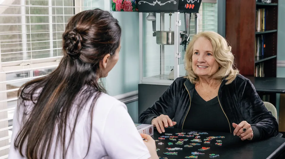 a woman sitting at a table with another woman looking at her