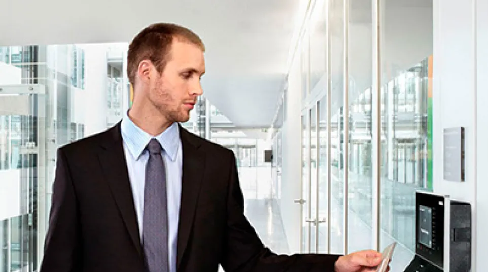 Businessman in suit using access card at modern office building's secure entry point