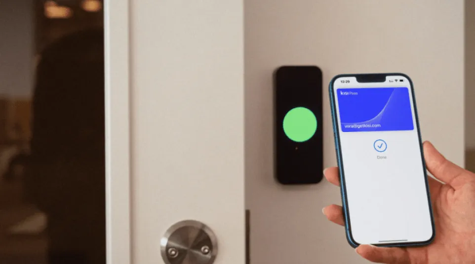 Person holding smartphone with digital key app unlocking a door with electronic access control system.