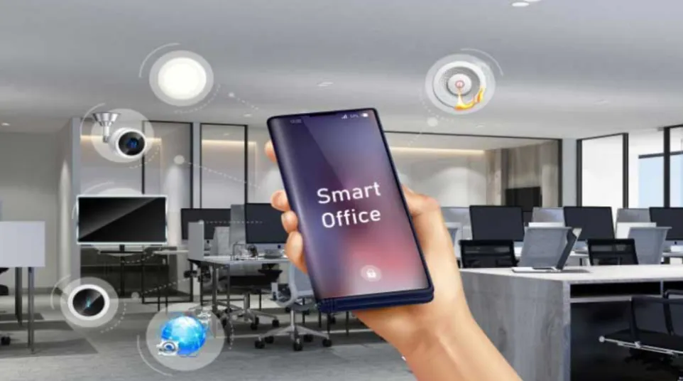 Hand holding smartphone displaying Smart Office app controlling devices in a modern office workspace environment.