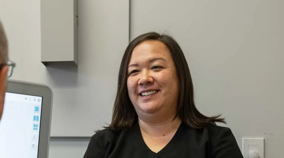 Smiling healthcare professional conversing with a patient in a modern clinical office setting.