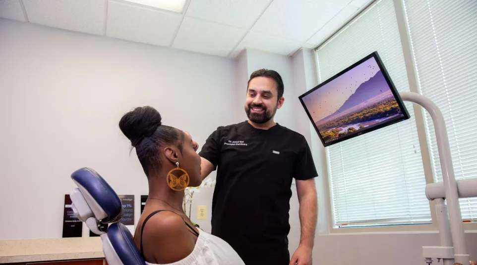 Dentist consulting with a female patient in a modern dental office with a scenic monitor display.