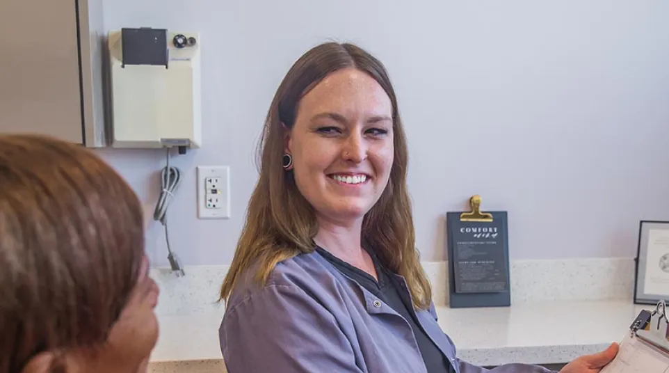 Dentist explaining dental model to smiling elderly woman in clinic chair during consultation