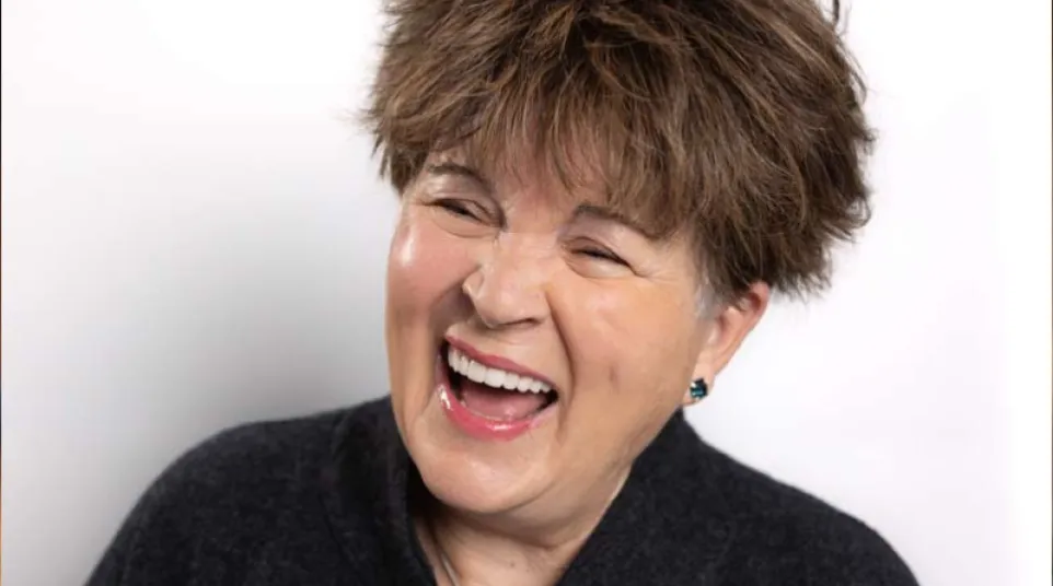 Smiling woman with short brown hair showcasing dental veneers, crowns, and implant results.