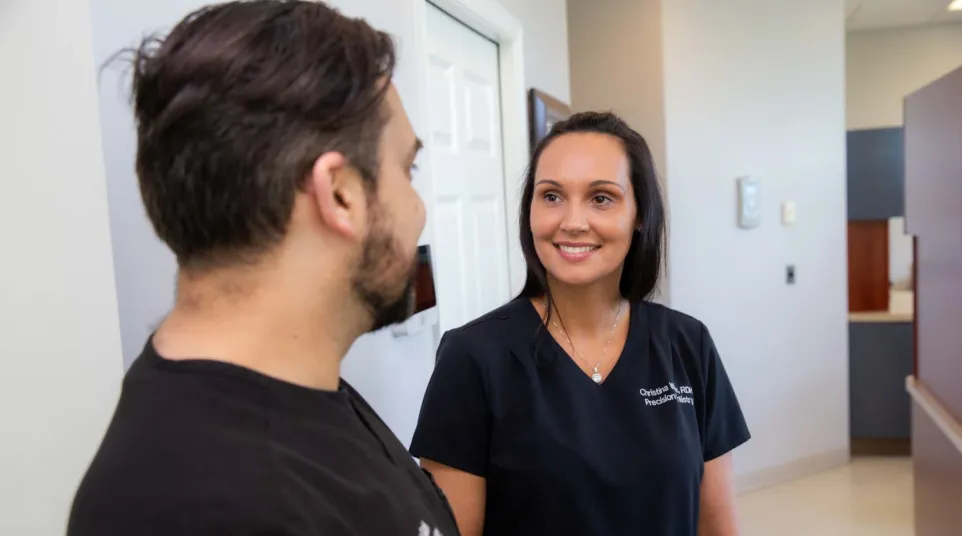 Female medical professional in black scrubs talking to male colleague in a clinical office setting