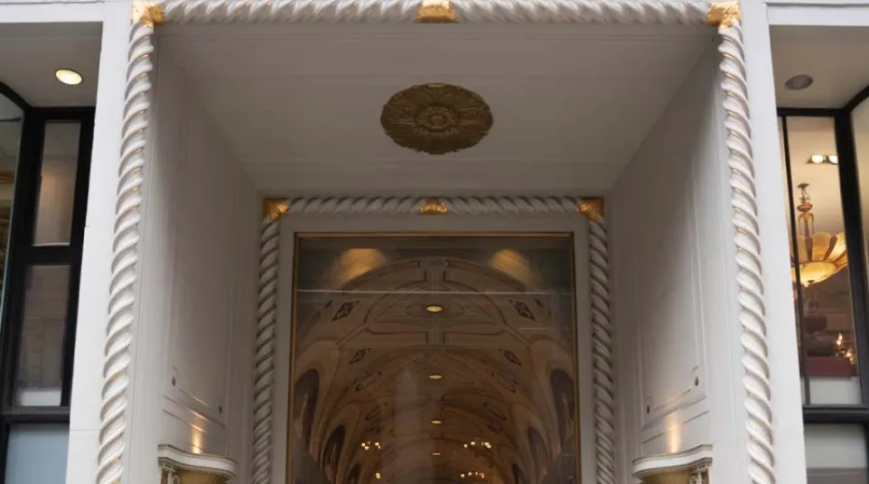 Entrance to the Bar Building with ornate white and gold detailing and a glass door beneath an arched ceiling.