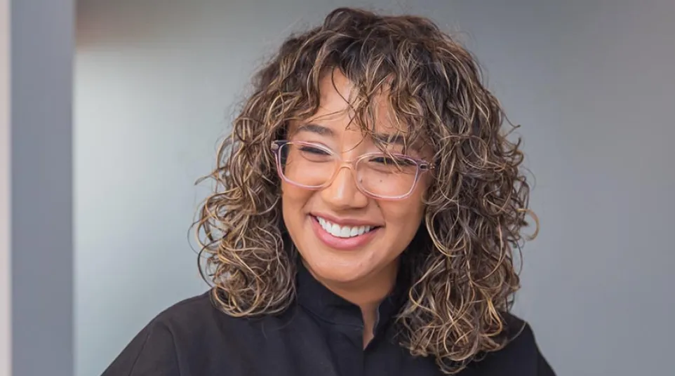 Two healthcare professionals in black scrubs smiling and discussing documents in a medical office.