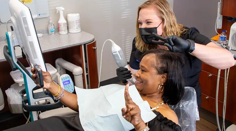 Dentist and patient smiling and posing for a selfie during dental checkup in modern clinic.