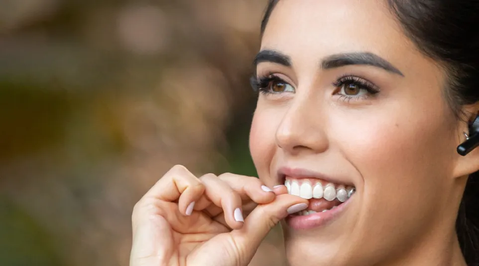 Clear Invisalign aligner against a blue background with Invisalign provider logo visible.