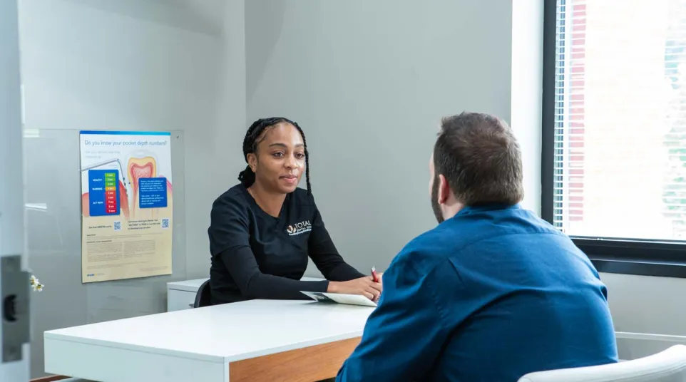 Dental professional discussing oral health with a patient in a bright, modern consultation room.