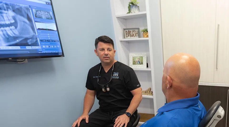 Dentist discussing dental X-ray results with patient seated in examination chair at clinic