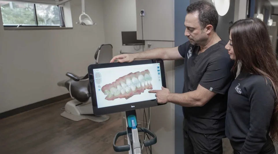 A dentist showing a 3D dental model to a patient in a modern clinic setting.