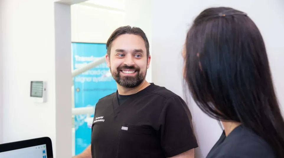 Dentist explaining dental health visuals to female patient in modern dental clinic setting.