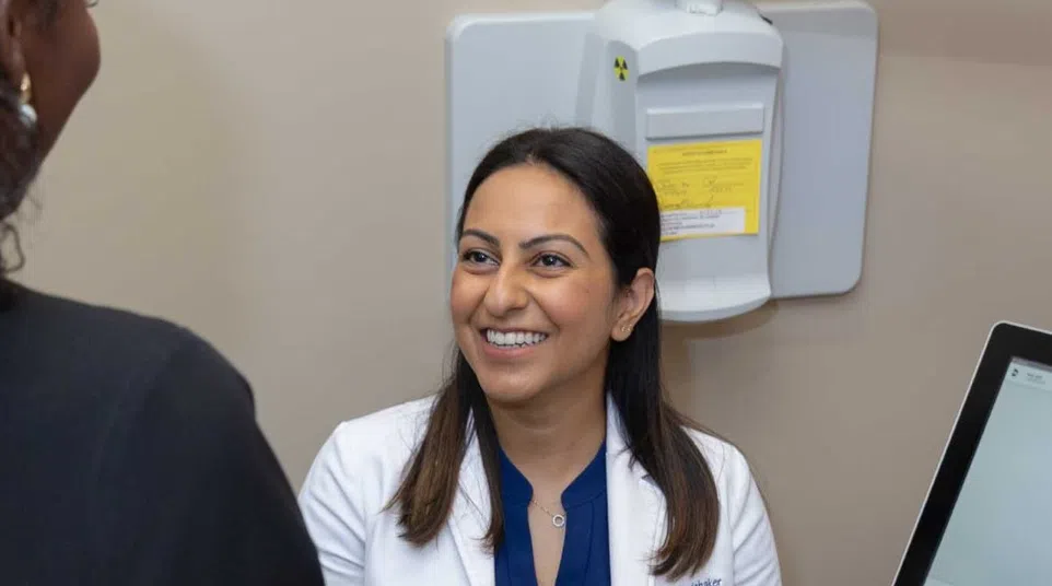 Dentist consulting with patient next to digital dental imaging equipment displaying teeth scan.