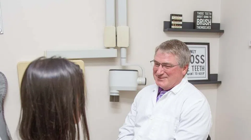 Dentist in white coat consulting female patient in dental office with dental equipment and health posters