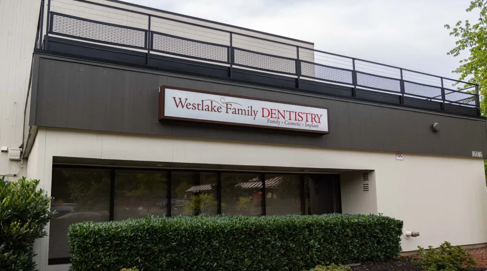Exterior view of Westlake Family Dentistry clinic with signage and greenery under a clear sky.