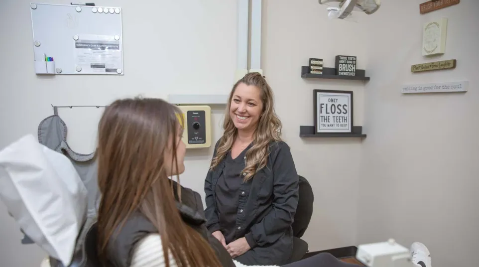 Dentist smiling and talking to female patient in a dental office with oral health decor.