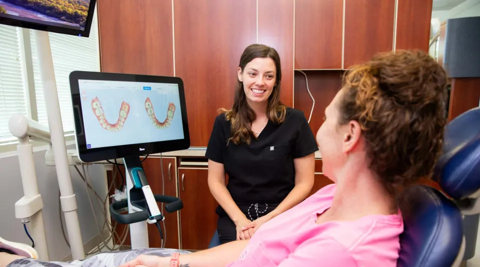 Dental professional discussing 3D teeth scan results with a patient in a modern dental office.