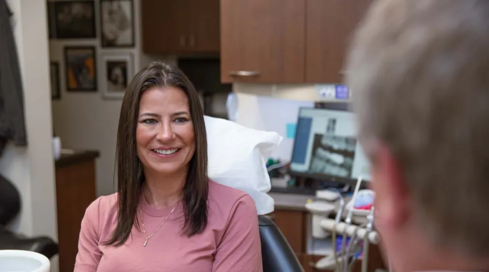 Smiling woman sitting in dental chair during consultation with dentist in modern clinic.
