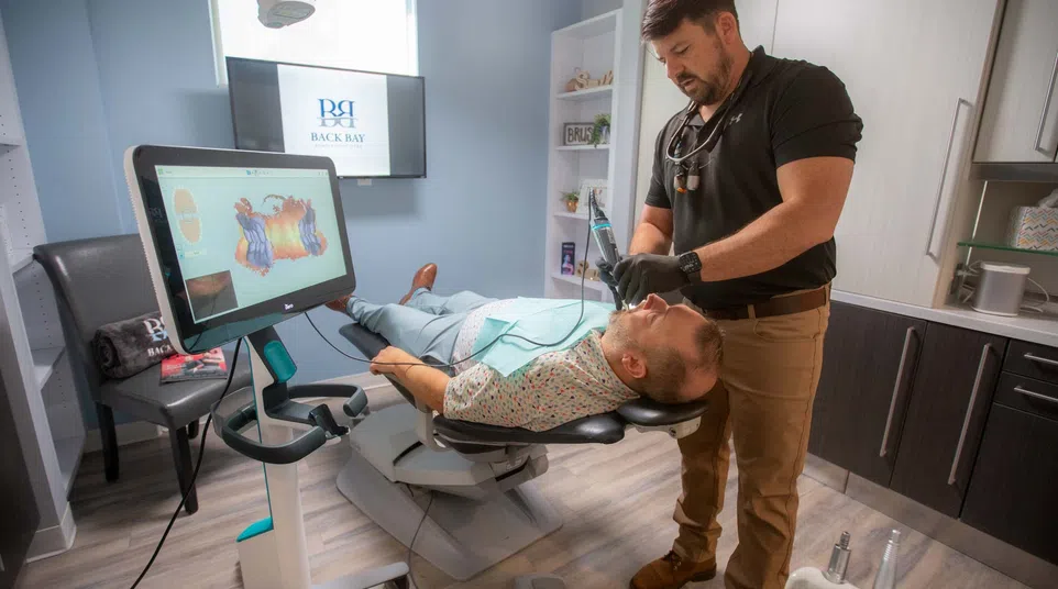 Dentist performing dental treatment on patient in modern clinic with digital imaging technology nearby