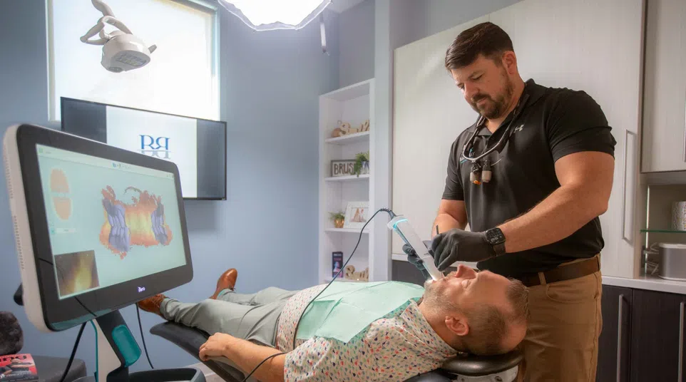 Dentist using digital scanner on patient lying in modern dental office for a 3D mouth scan