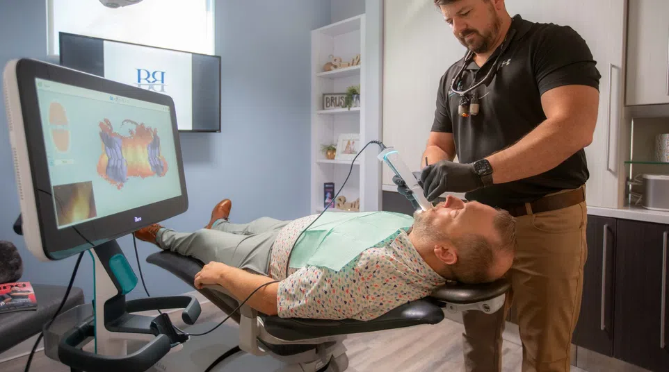 Dentist using digital scanner on patient lying in modern dental office for a 3D mouth scan