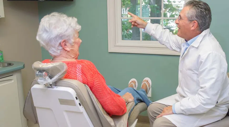 Dentist explaining dental X-ray results to senior woman patient in dental office consultation.