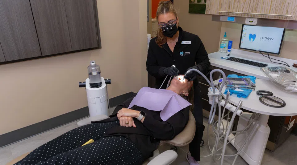 Dentist wearing black mask treating patient reclining in dental chair in modern clinic