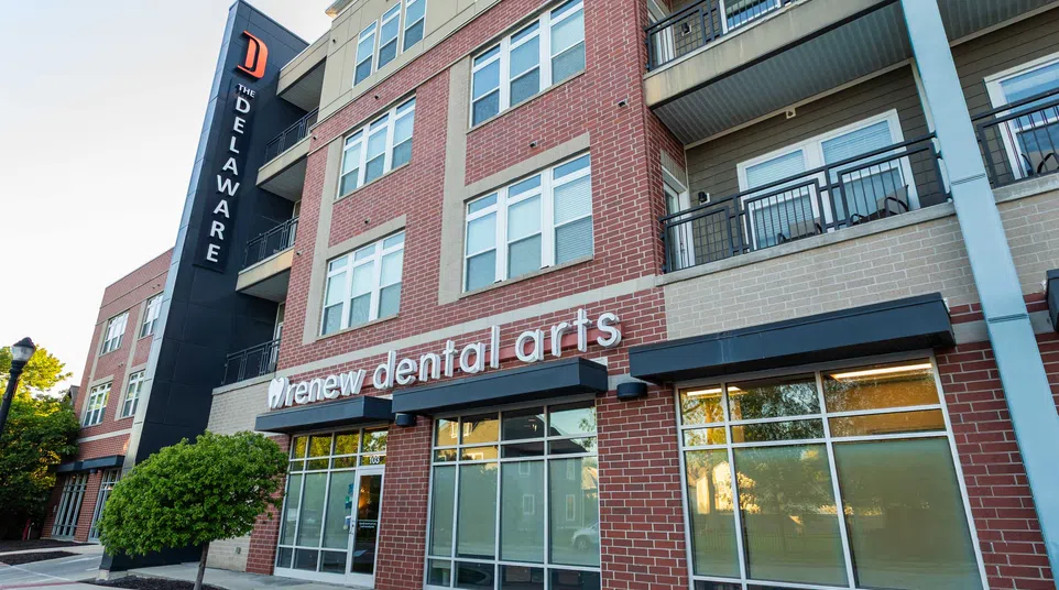 Exterior view of Renew Dental Arts clinic in a modern brick building under clear sky.