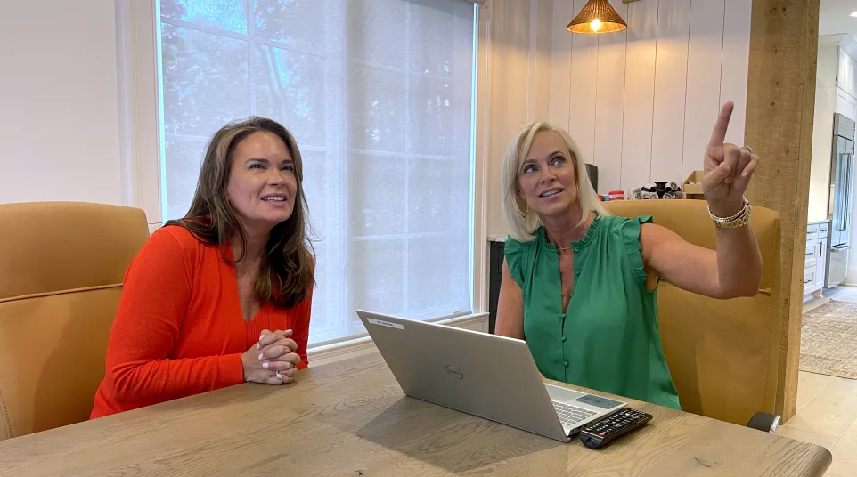 a couple of women sitting at a table with a laptop