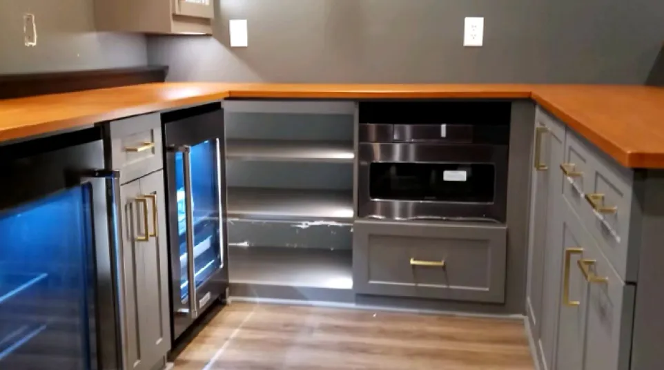 Modern kitchen with gray cabinets, wooden countertops, mini fridge and wood laminate flooring.