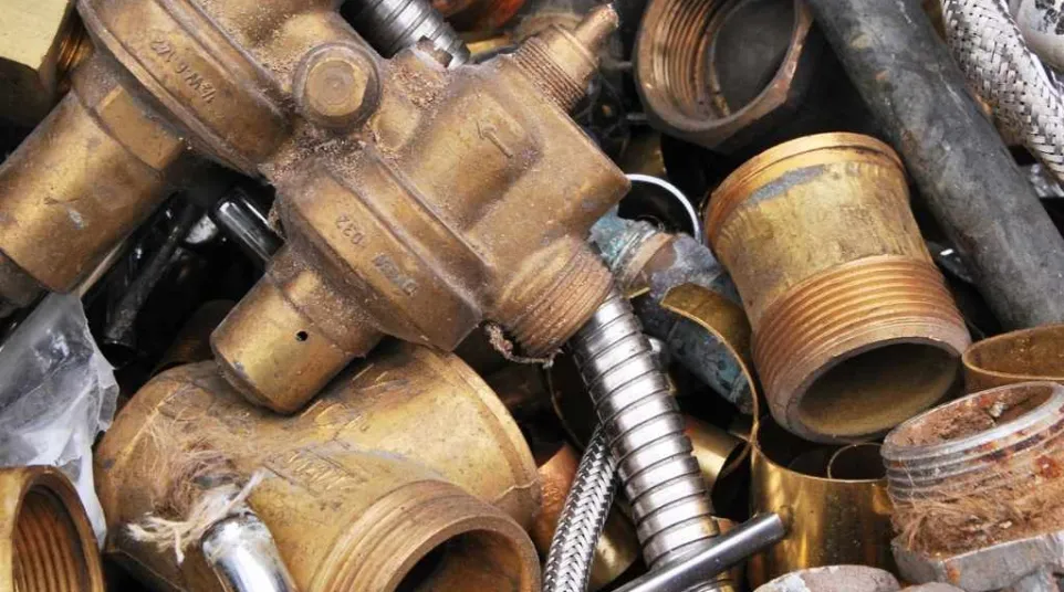 Close-up of old brass plumbing parts and fittings mixed with metal pipes and flexible hoses.