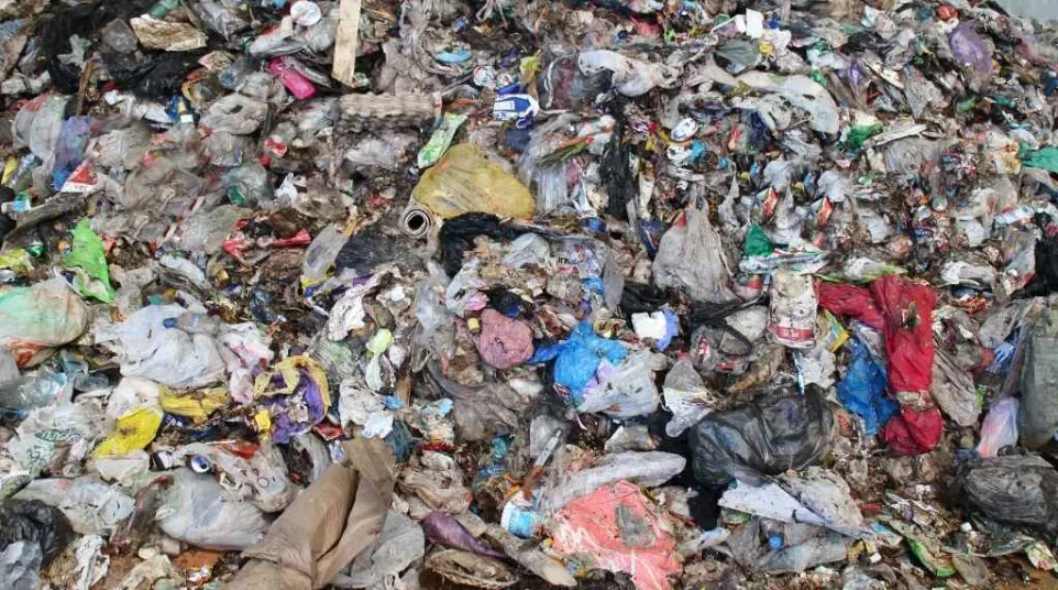 Large heap of mixed household garbage pile including plastics, papers, and organic waste in a landfill.