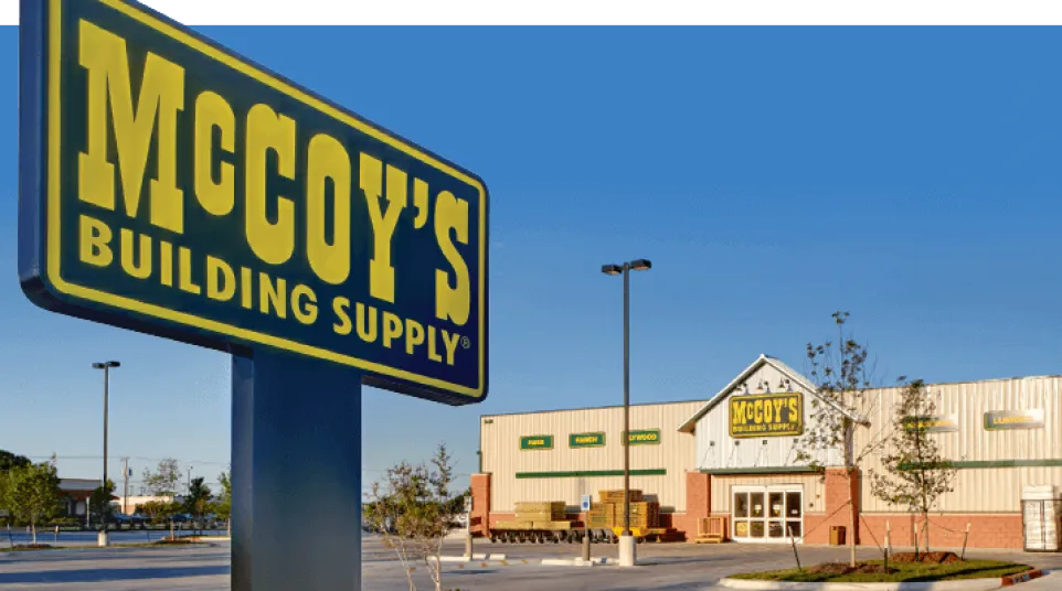 McCoy's Building Supply store exterior and large yellow and blue sign in a clear sky parking lot.