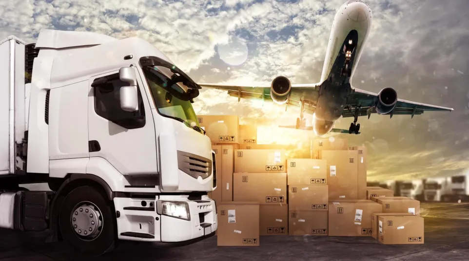 White delivery truck and airplane over stacked cardboard boxes at sunset in logistics hub.