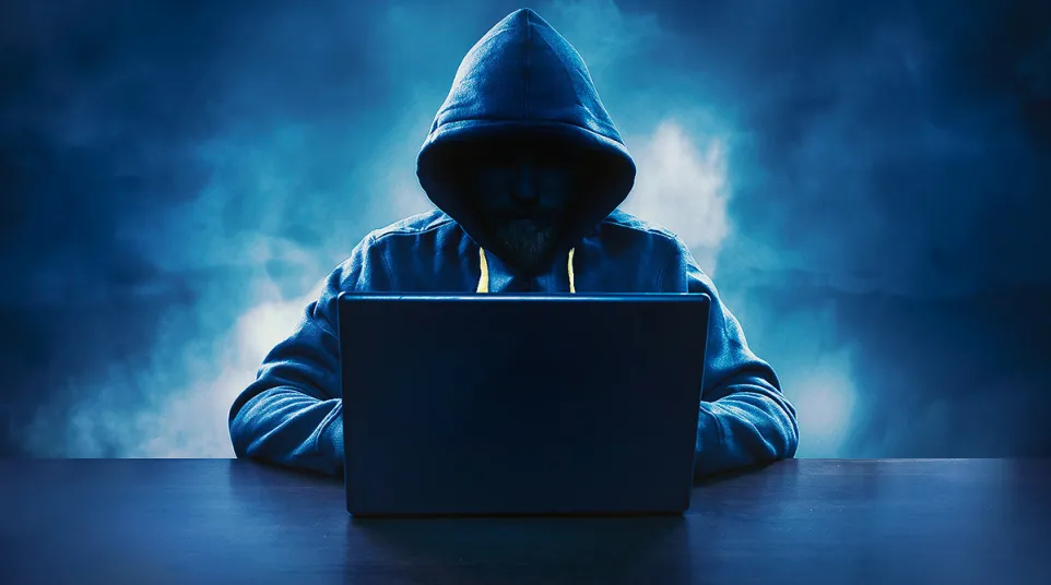 a person wearing a hoodie and using a laptop