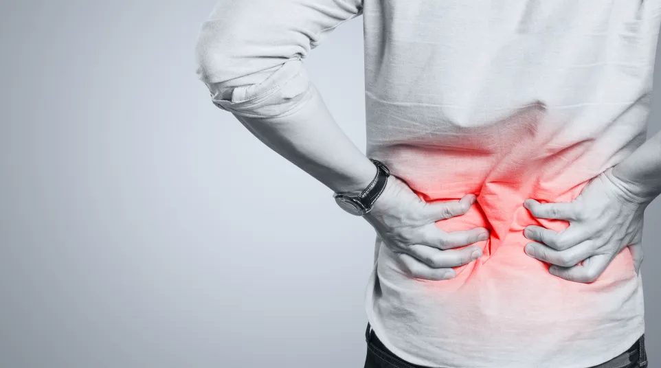 Man holding lower back in pain with red highlight indicating acute lower back pain or injury.