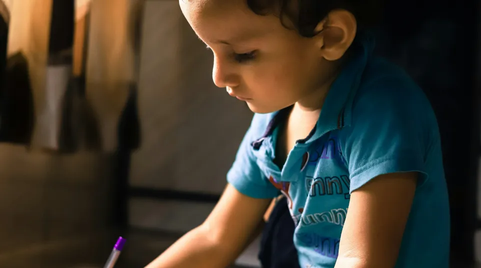 a young boy writing on a piece of paper