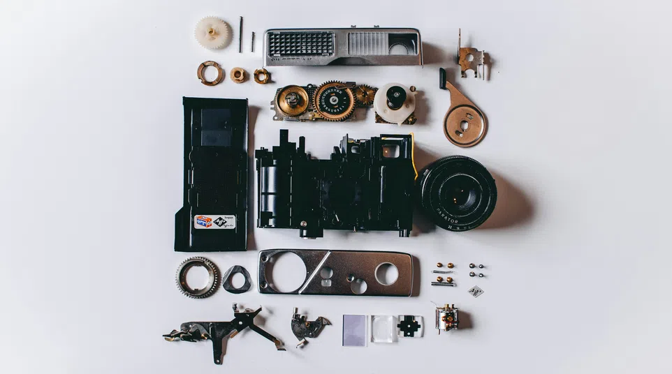Disassembled vintage camera parts neatly arranged on a white background viewed from above