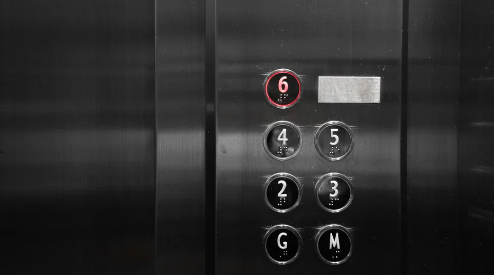 Elevator control panel with circular buttons numbered 2-6, G, M; button 6 is lit with a red ring.