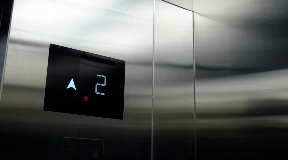 Digital elevator panel showing floor 2 and up arrow in a stainless steel elevator interior