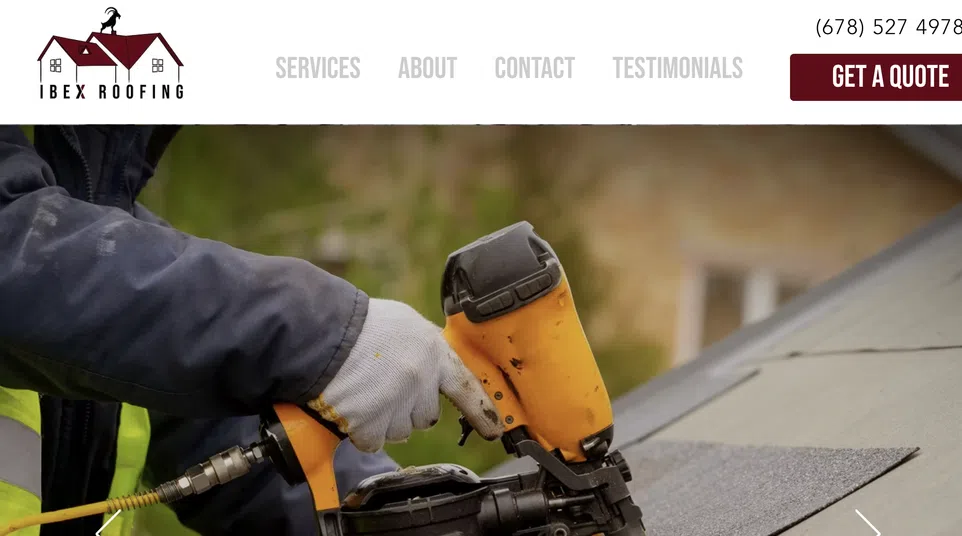 Close-up of worker using nail gun to install roofing shingles on house roof outdoors
