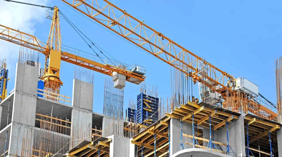 Construction site featuring a yellow crane and reinforced concrete structures under blue sky.