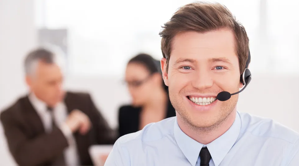 Smiling customer service representative with headset in a modern office setting.