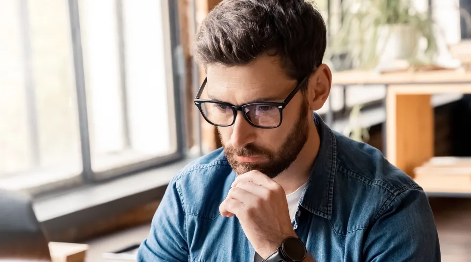 Focused man working on a laptop in a modern office environment with natural light.